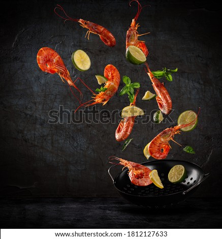 Fresh sea food flying into a pan on dark background