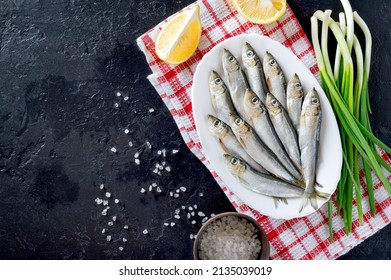 Fresh sea small fish on a plate on a dark background. Top view, flat lay. The concept of fresh, healthy seafood. - Powered by Shutterstock