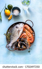 Fresh Seafood: Shrimp, Mussels And Dorado Fish, On Ice In A Copper Cup, With Lemon, Lime, Sea Salt. On A Blue Background. Top View Overhead View   Copy Space