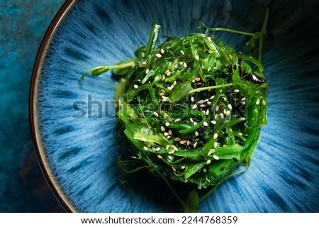 Fresh seaweed salad with sesame on a blue abstract plate. Top view. Japan food background.