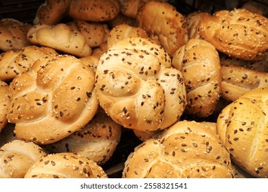 Fresh sesame Kaiser rolls on a bakery shelf. Golden brown buns topped with sesame seeds. Crisp and freshly baked rolls for breakfast or sandwiches. Bakery display of classic bread rolls. - Powered by Shutterstock