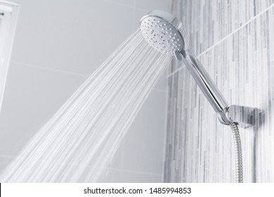 Fresh shower behind wet glass window with water drops splashing. Water running from shower head and faucet in modern bathroom. - Shutterstock ID 1485994853