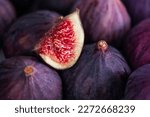Fresh slice of fig lying on a heap of ripe figs. Heap of tasty organic figs