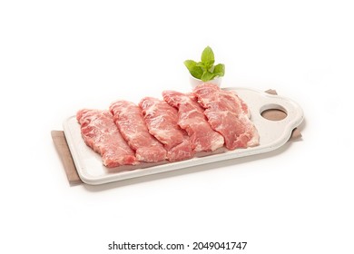fresh sliced pork jowl in a white dish with some decorative spices and herbs close-up. isolated white background