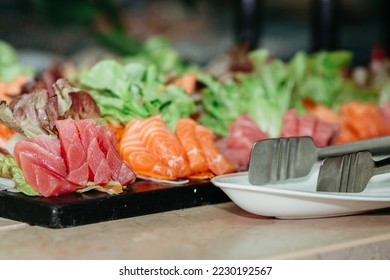 Fresh sliced tuna and salmon sashimi presentation at the seafood market buffet in the restaurant hotel. - Shutterstock ID 2230192567
