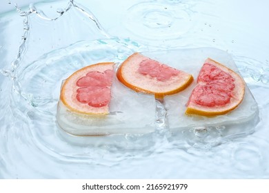 Fresh slices of grapefruit frozen in ice with water splash on white background