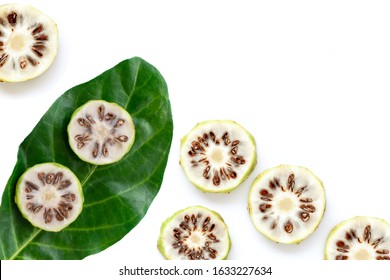 Fresh slices of noni fruit or morinda citrifolia (commom name as indian mulberry, cheese fruit) with green leaf isolated on white background. Top view. Flat lay.