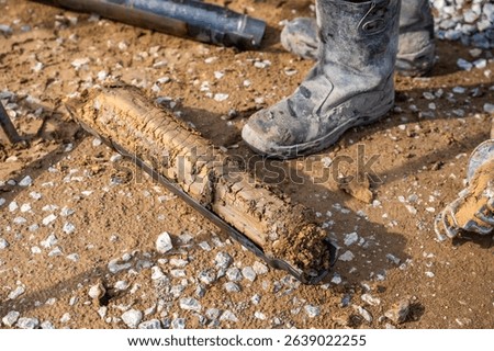 Fresh soil core sample placed on the ground after drilling. Subsurface material collected for geotechnical testing and laboratory analysis. High quality photo