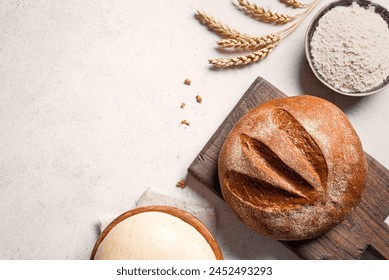 Fresh sourdough bread and ingredients. Loaf of bread on cutting board, ball of dough and flour on white table, baking background, copy space, top view. - Powered by Shutterstock