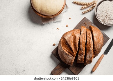 Fresh sourdough bread and ingredients. Sliced loaf of rye bread on cutting board, yeast dough and flour on white table, baking background, copy space, top view. - Powered by Shutterstock