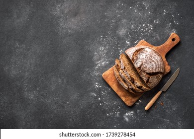 Fresh Sourdough Bread  on black background. Fresh baked homemade sliced rye bread, top view, copy space.