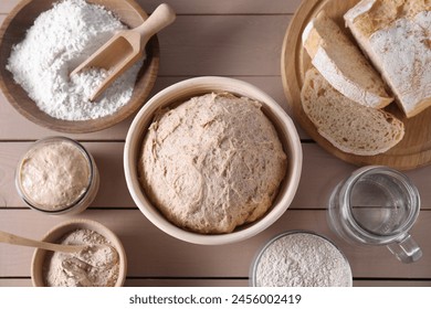 Fresh sourdough, flour, water and bread on wooden table, flat lay