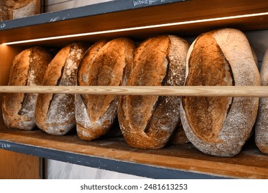 Fresh sourdough loaves in an Italian bakery shop. Delicious loaves of bread displayed on wooden shop shelf. - Powered by Shutterstock