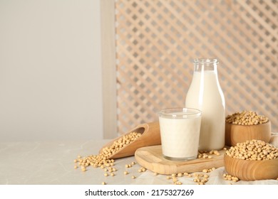 Fresh soy milk and beans on light grey table, space for text