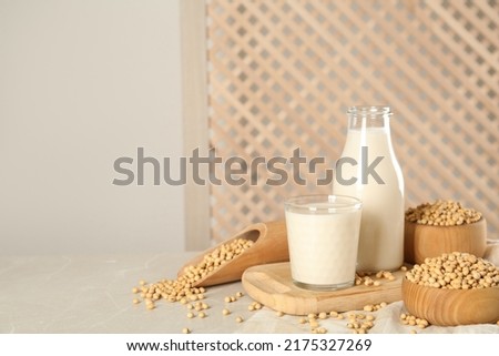 Fresh soy milk and beans on light grey table, space for text