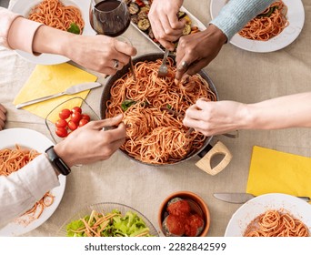 Fresh spaghetti with tomato sauce close up, humand hand using forks to pick up food, from above - Powered by Shutterstock