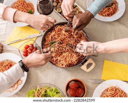 Fresh spaghetti with tomato sauce close up, humand hand using forks to pick up food, from above