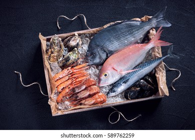 Fresh Spanish Fish And Seafood In Wooden Box On Black Stone Table