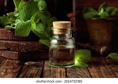 Fresh spearmint leaves and a small bottle with essential mint oil. Herbal medicine ingredients on an old wooden background.