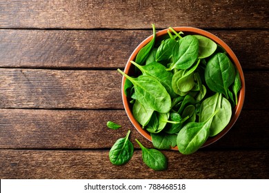 Fresh spinach leaves in bowl on rustic wooden table. Top view. - Shutterstock ID 788468518