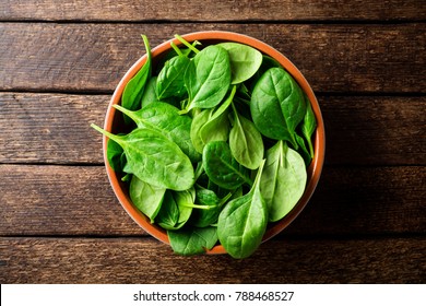 Fresh Spinach Leaves In Bowl On Rustic Wooden Table. Top View.