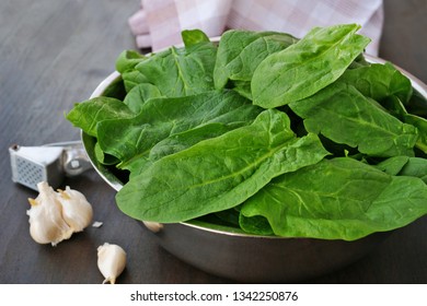 Fresh spinach leaves in metallic bowl over dark wooden table
