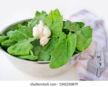 Fresh spinach leaves in metallic bowl over light background