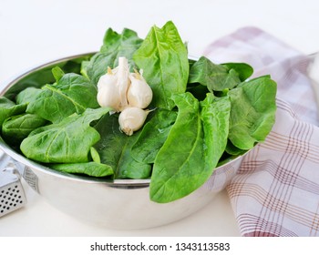 Fresh spinach leaves in metallic bowl over light background