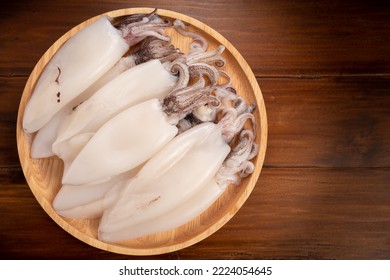 Calamar espléndido fresco sobre plato de madera, calamar fresco sobre fondo de madera, 