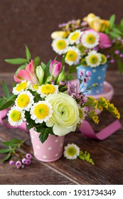 Fresh spring flowers in little vases, rustic wooden background