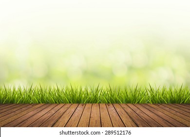 Fresh Spring Grass With Green Nature Blurred Background And Wood Floor Pattern, Design Element For Display Product In Natural Environment And Eco Friendly Concepts