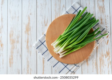 Fresh spring onions or scallions on a cutting board on white wooden table, top view. - Powered by Shutterstock