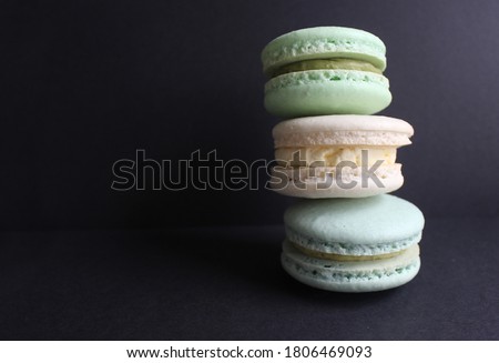 Fresh Stack of three multicolored Macaron or Macaroons on Black background, pastel colors, stacked, colorful, cafe desserts
