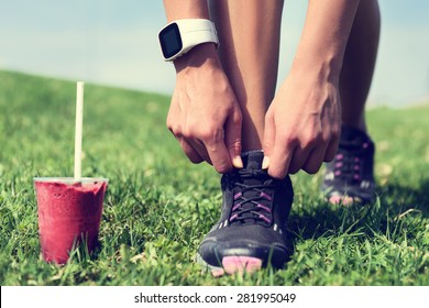 Fresh Start On Weight Loss - Runner Tying Laces With Fruit Smoothie Wearing Smartwatch For Cardio. Detox, Clean Eating And Diet. Woman Getting Ready For Jogging Workout. Closeup Of Running Shoes.