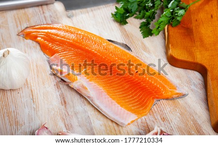 Fresh steelhead trout fillet on wooden surface with seasonings ready for cooking