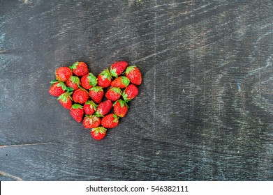 Fresh strawberries array heart shape on old wooden background. Love concept. Valentine's Day Concept
