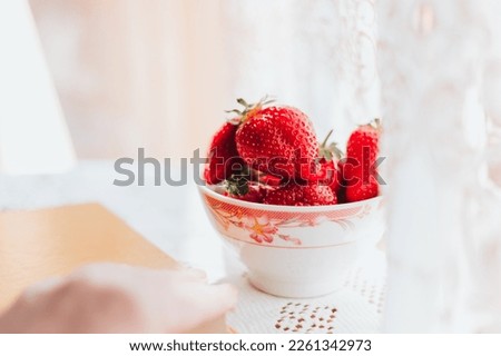 Fresh strawberries in the ceramic bawl on the table and a book. Morning leisure time