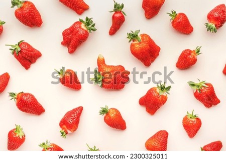 Fresh strawberries, different in shape and size, flat lay, light beige background, top view