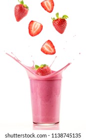Fresh strawberries falling into a glass to make a delicious strawberry smoothie. White background.