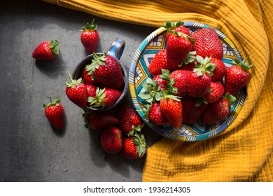 A lot of fresh strawberries on a table. Top view photo of juicy fruits, blue ceramic plate and cup, yellow linen kitchen towel. Healthy eating concept. 
 - Powered by Shutterstock