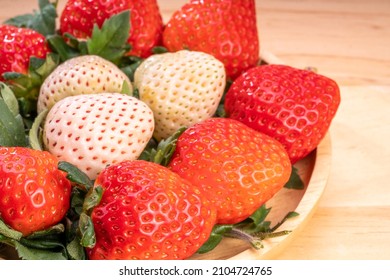 Fresh strawberries in a wooden basket on wooden background, Red Strawberries and white strawberries Pine berry or Hula strawberry in Bamboo basket.