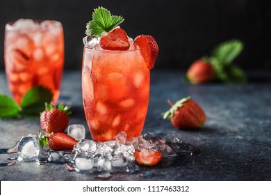 Fresh strawberry cocktail. Fresh summer cocktail with strawberry and ice cubes. Glass of strawberry soda drink on dark background.