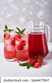 Fresh Strawberry Lemonade With Ice And Mint In Glasses And Jug On White Table, Copy Space. Cold Summer Drink. Sparkling Glass With Berry Cocktail