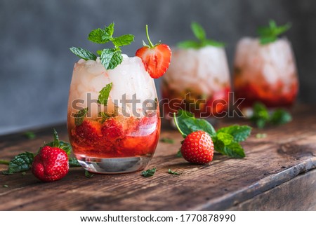 Fresh strawberry mojito drinks. There are three drinks on a vintage wooden dark table.  The cocktails or mocktails are decorated with strawberries and fresh mint. Copy space room for text.