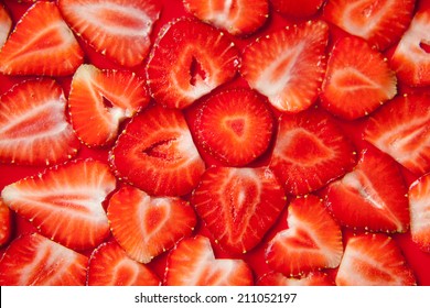 Fresh strawberry slices on red background. All created as a flower pattern. Fresh summer wallpaper or background, healthy life and food.