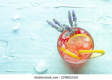 Fresh Summer Cocktail Or Mocktail With Lemon And Lavender, A Cold Citrus Drink With Ice, Shot From Above On A Blue Background With A Place For Text