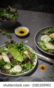 Fresh summer salad with cucumber, melon, avocado and fresh oregano served on ceramic plates.