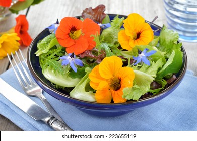 Fresh summer salad with edible flowers nasturtium, borage flowers in a bowl. - Shutterstock ID 223655119