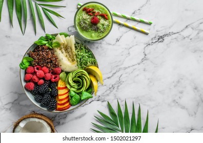 Fresh summer salad with quinoa, peach, micro greens, avocado, berries, coconut, melon on light marble background with tropical leaves. Healthy food, clean eating, Buddha bowl salad, detox, top view