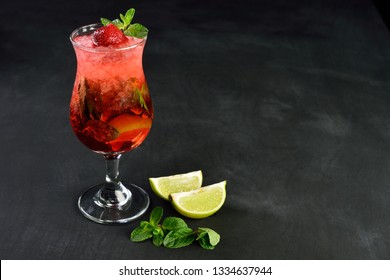 Fresh summer strawberry mojito drink with ice, served on black wood